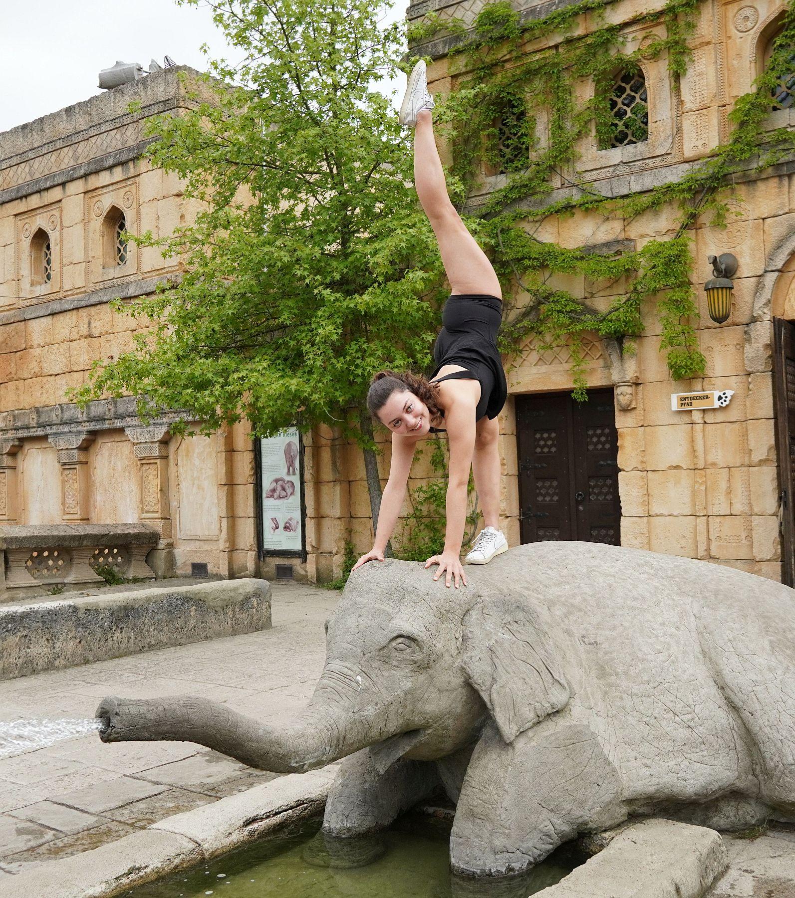 Eine Akrobatin turnt auf dem Steinelefanten