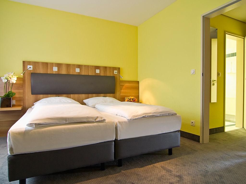 GHOTEL hotel & living Hannover: Helles Hotelzimmer mit gelber Wand