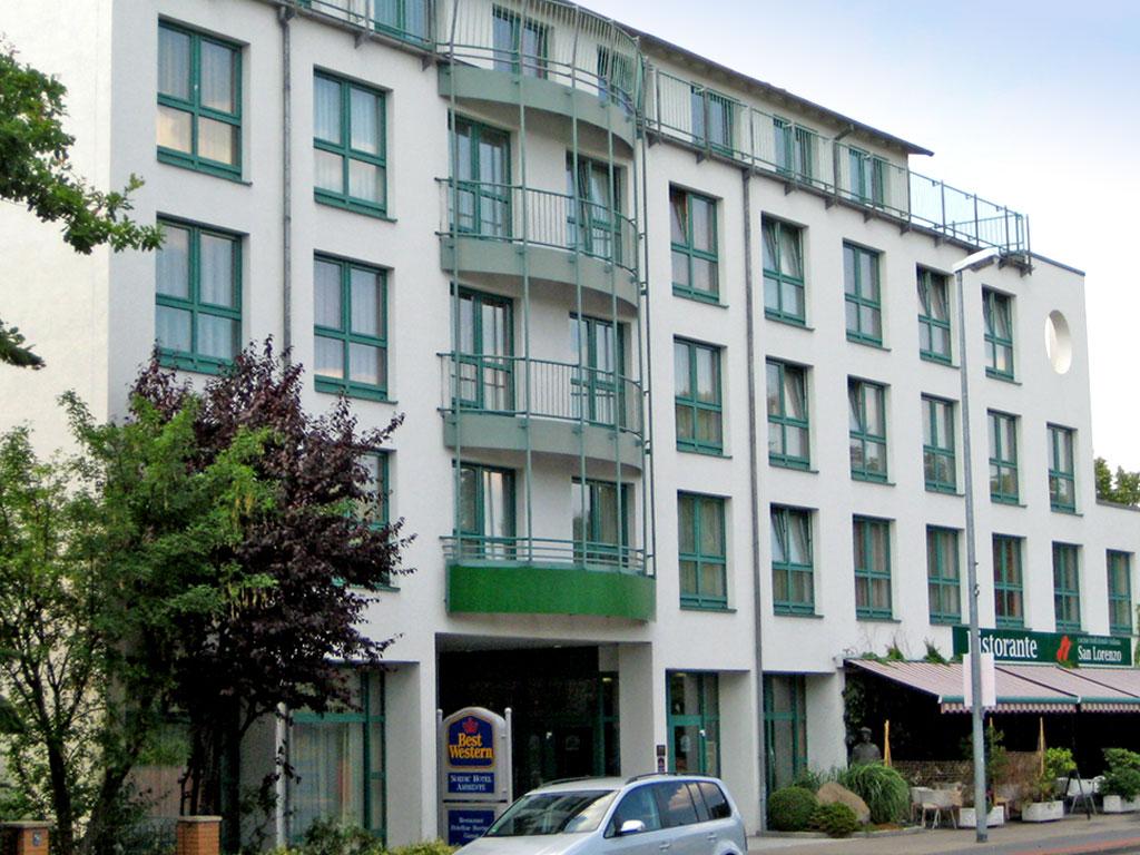 Fassade des Hotel Ambiente by Tulip Inn: Gepflegtes Gebäude mit grünen Fensterrahmen, anliegendem Restaurant
